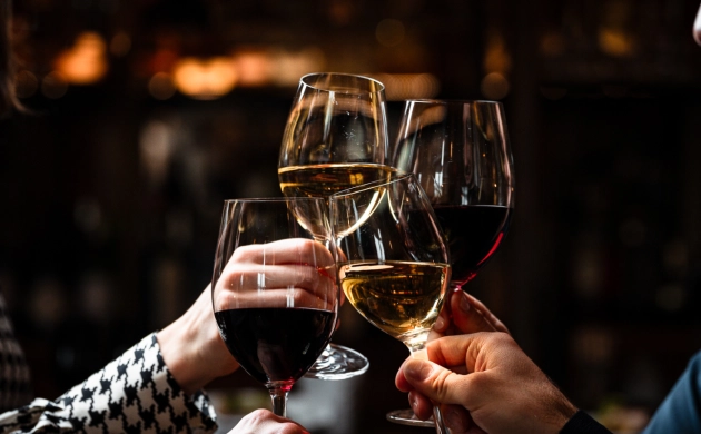 Friends toasting with glasses of red and white wine in a warm atmosphere, celebrating a hen party or stag party in the dark in Lisbon